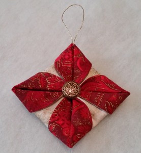 With the same thread, sew a button or charm to the center of the ornament. Knot and cut off the thread. Add a loop of thin ribbon or metallic cord at the top for hanging.