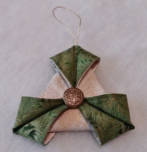With the same thread, sew a button or charm to the center of the triangle. Knot and cut off the thread. Add a loop of thin ribbon or metallic cord at the top for hanging.